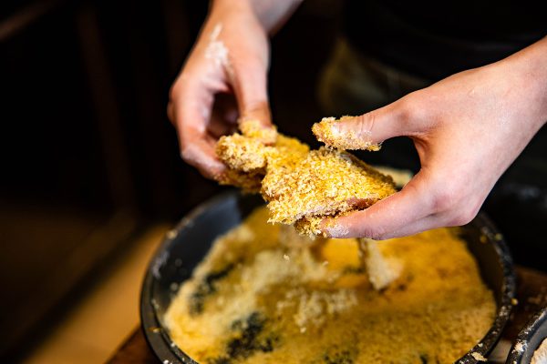 Person enjoying freshly cooked cornbread fritters in a pot