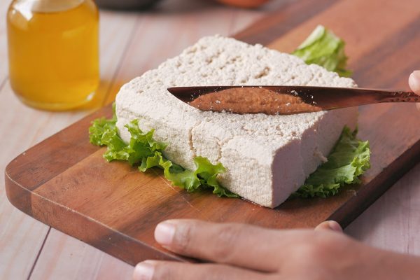 cutting slice of tofu on a chopping board on table ,